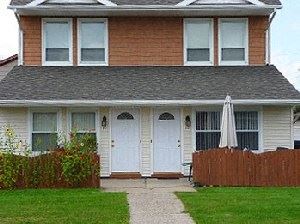 a house with two white doors and an umbrella in the yard