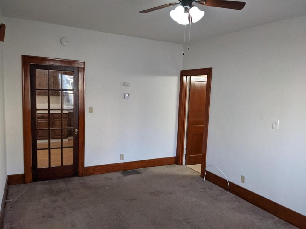 an empty living room with white walls and a ceiling fan