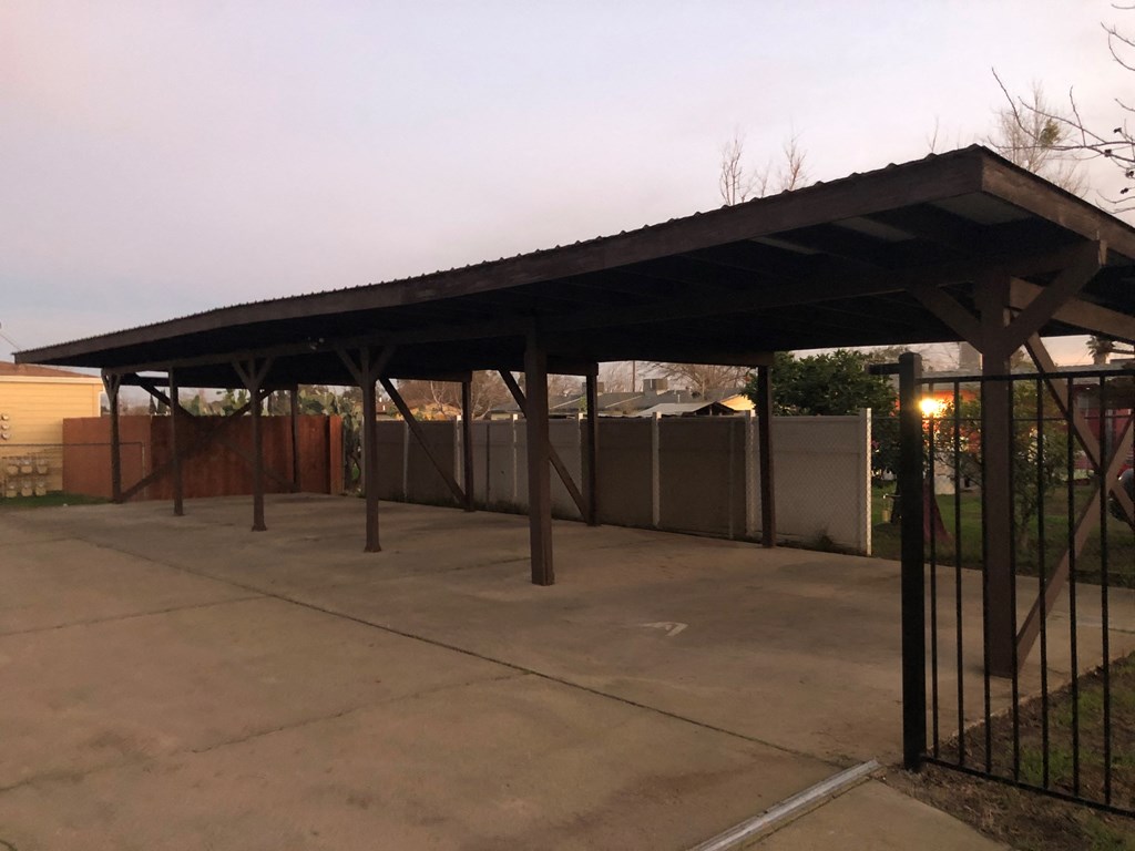 a covered parking lot with a fence and a building in the background