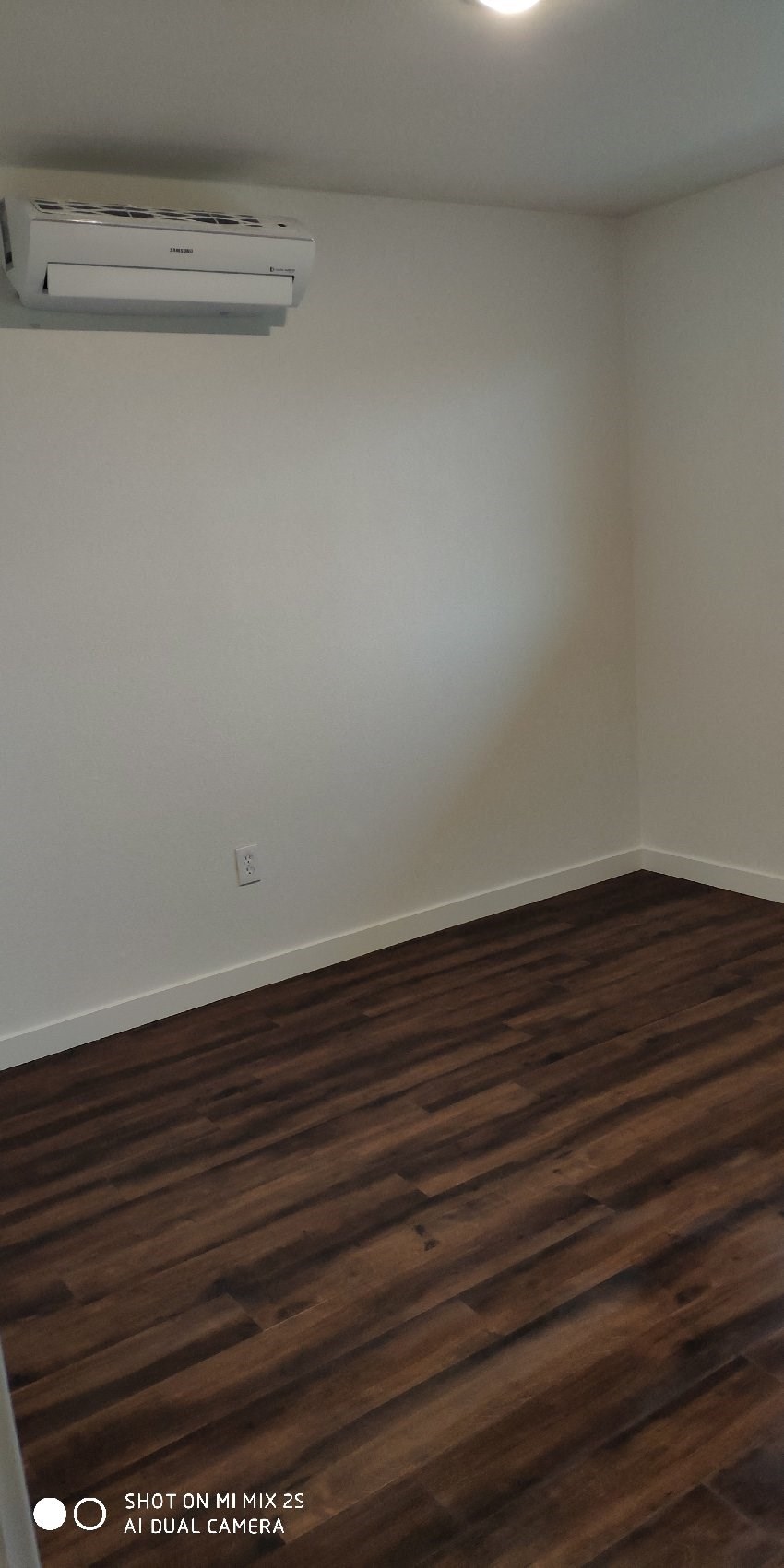 an empty room with wooden floors and a air conditioner