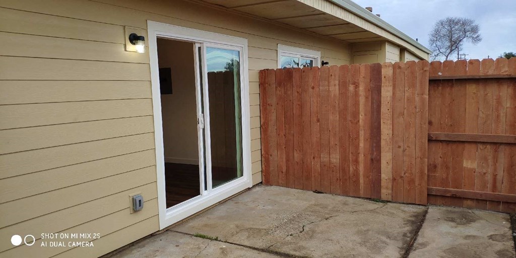 the backyard of a home with a fence and a patio door