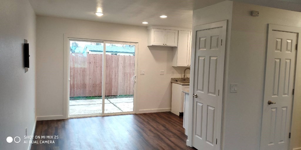an empty living room with a kitchen and a sliding glass door