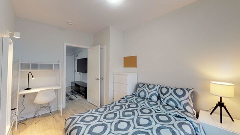 A bedroom with a bed, desk, and chair.