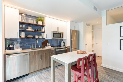 a kitchen with a white table and red chairs and a sink