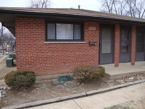 A red brick house with a green hose on the ground.