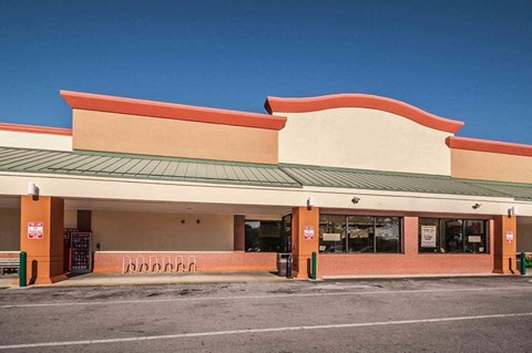 A storefront with a red and green roof and a parking lot in front.