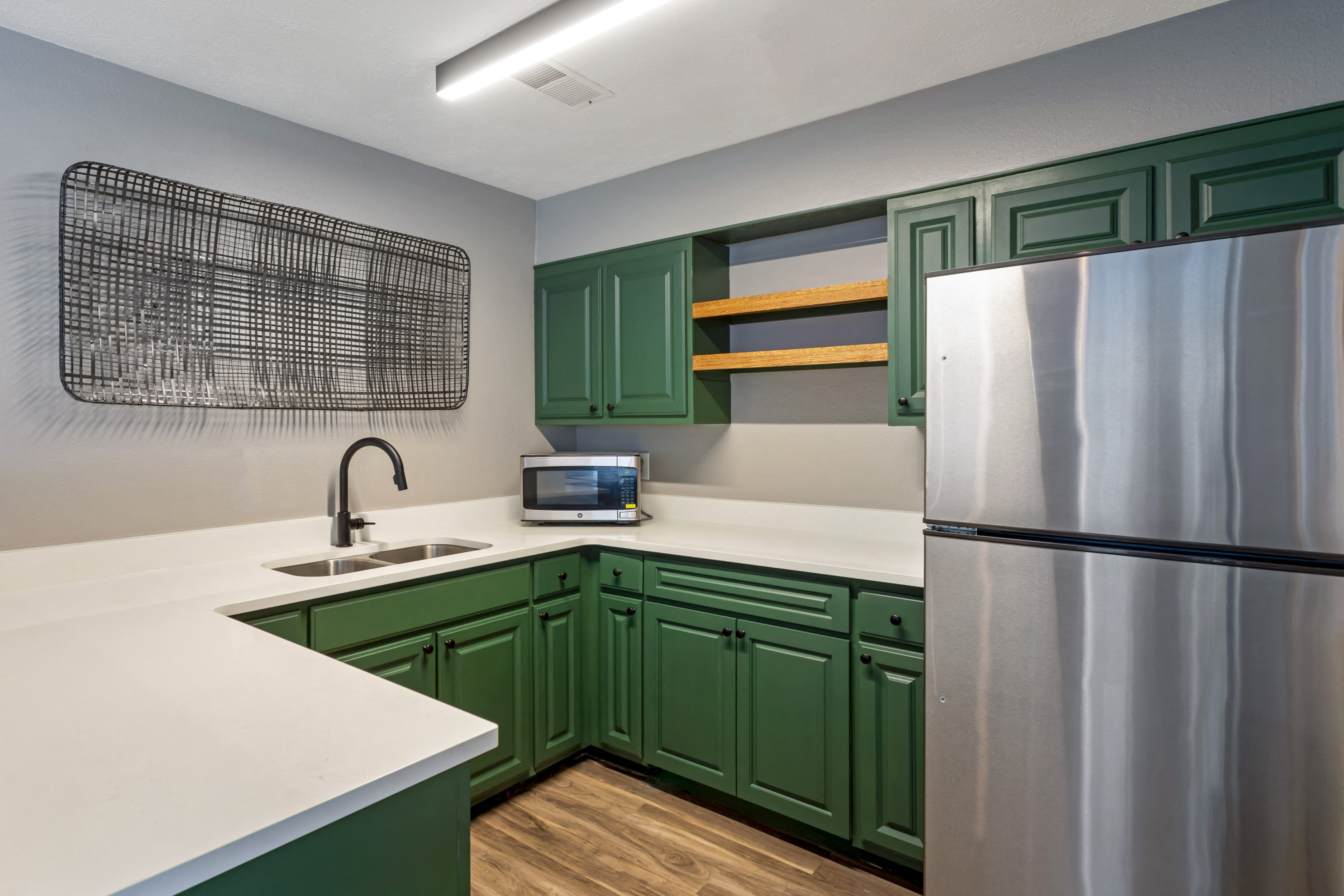 a kitchen with green cabinets and a stainless steel refrigerator