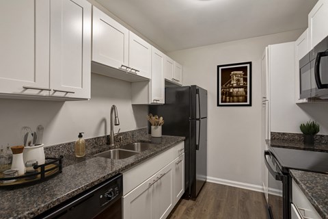 a kitchen with white cabinets and granite counter tops and a black refrigerator