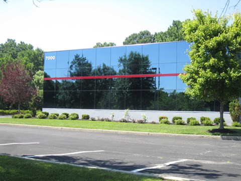 A large building with a glass facade and a red stripe on it.