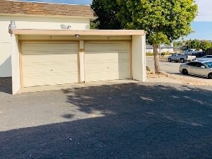 A garage door is closed and the garage door opener is on the top of the garage.