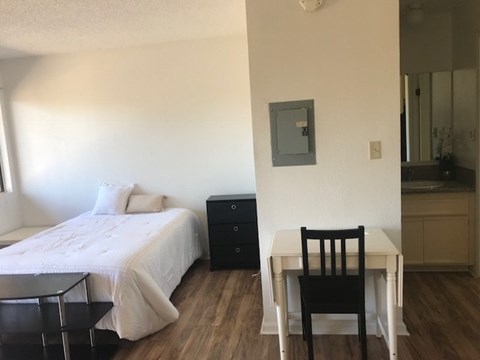 A bedroom with a bed, chair, and a small table.