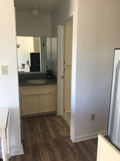 A kitchen with a white fridge and wooden floors.