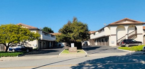 A residential street with houses on both sides and cars parked on the side.