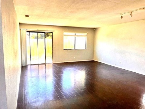Empty room with wooden floor and sliding glass door.
