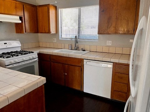 A kitchen with wooden cabinets and a white dishwasher.