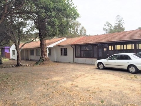 A white car is parked in front of a building with a red roof.