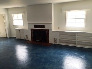 A room with a fireplace and two windows.