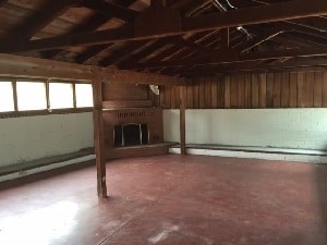 A room with wooden beams on the ceiling and a window on the left side.