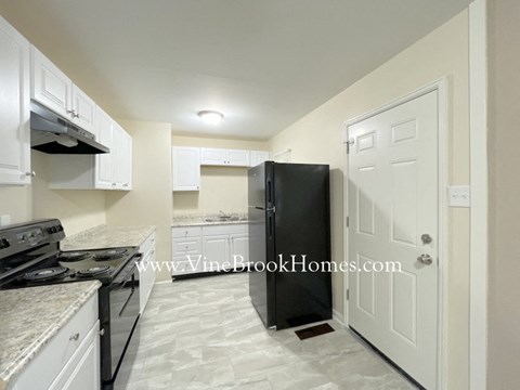 a kitchen with a black refrigerator and white cabinets