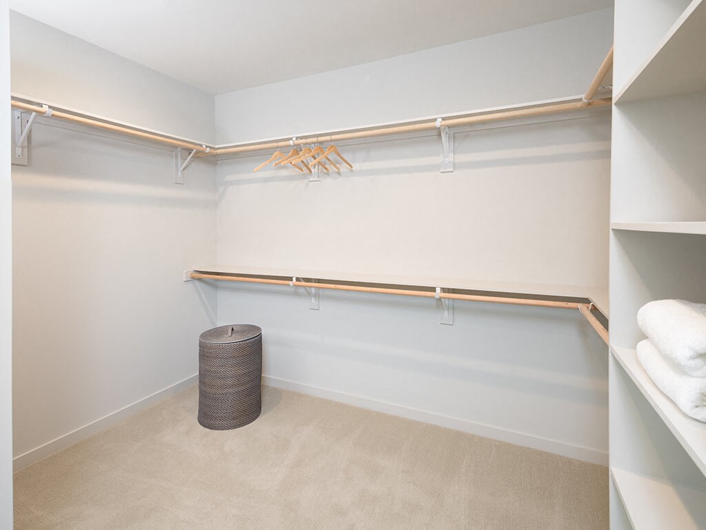 a walk in closet with shelves and a trash can