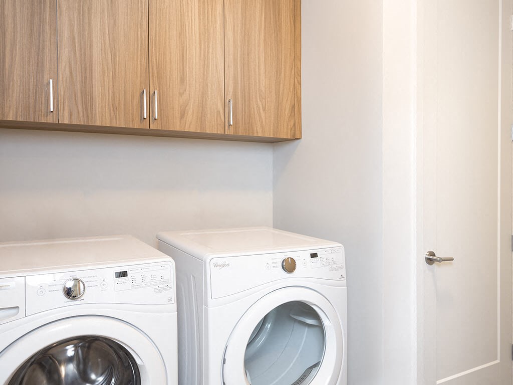 a washer and dryer in a laundry room with wooden cabinets