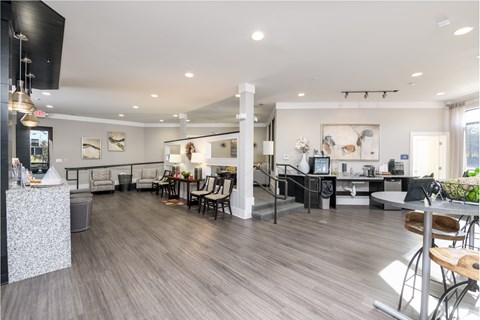 a communal room with tables and chairs and a kitchen and a tv