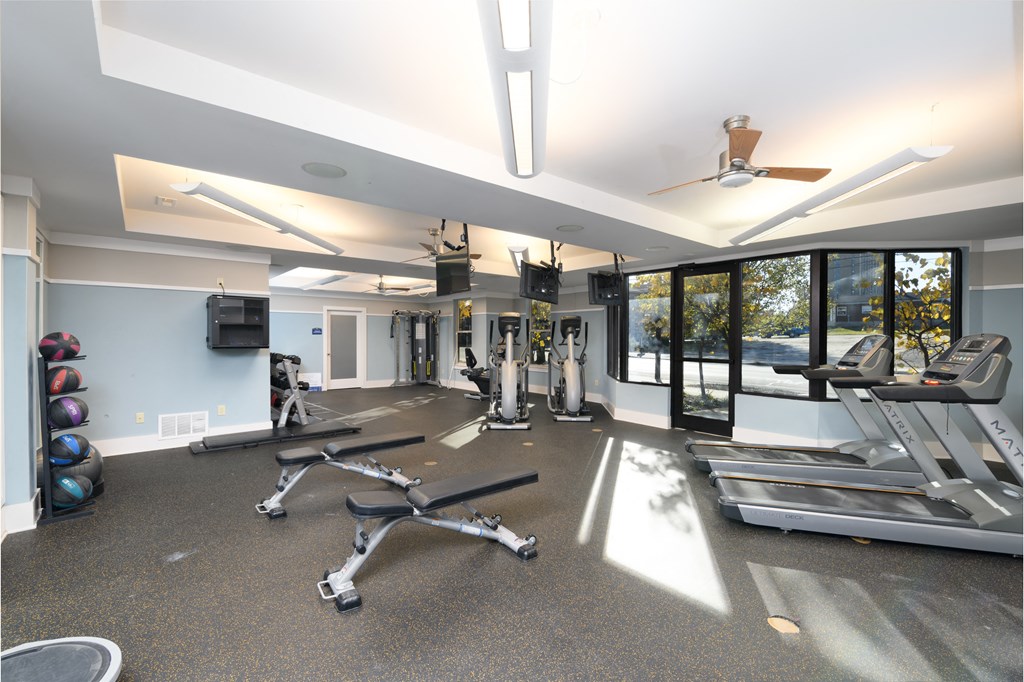 a gym with treadmills and other exercise equipment and windows