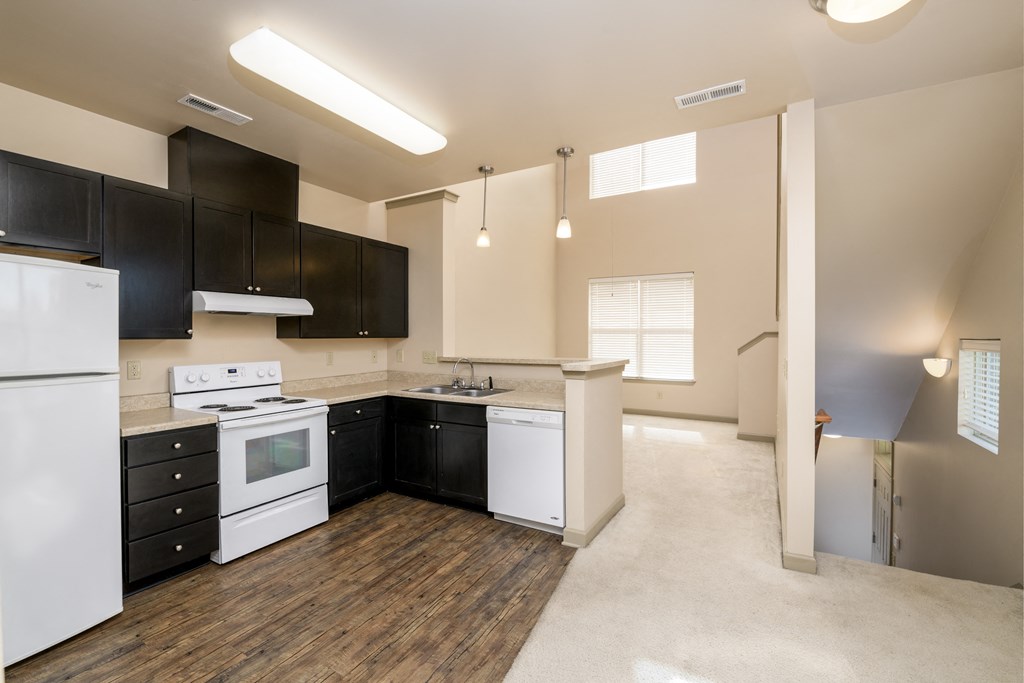 an empty kitchen with white appliances and black cabinets