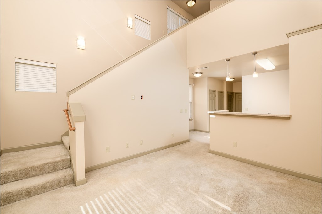 an empty living room with stairs and a kitchen in a building