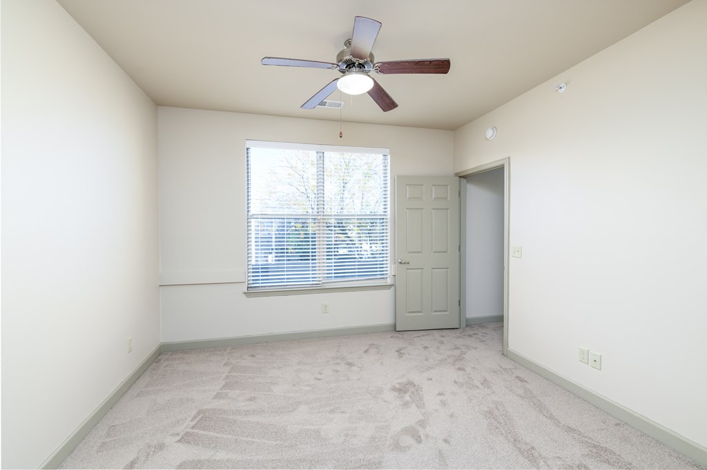 an empty living room with a ceiling fan and a window