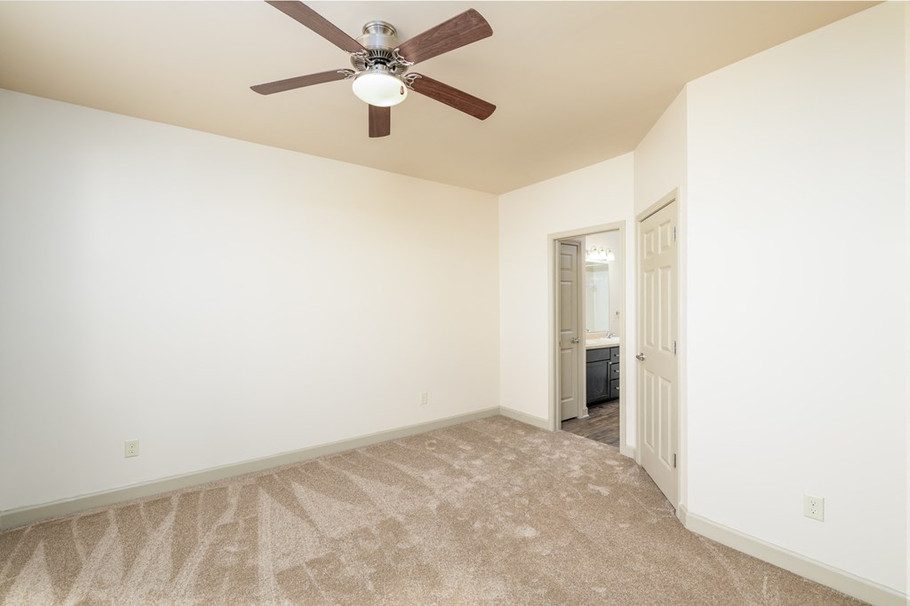 an empty living room with a ceiling fan and white walls