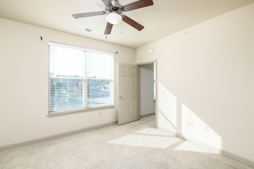 an empty living room with a ceiling fan and a window