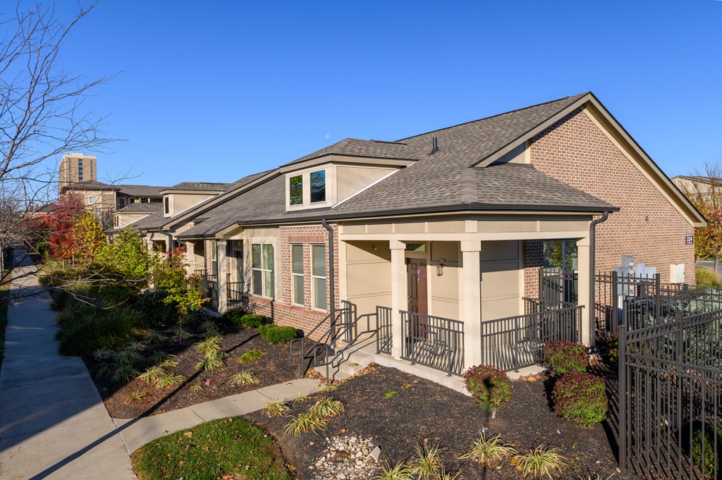 a brick house with a porch and a sidewalk in front of it
