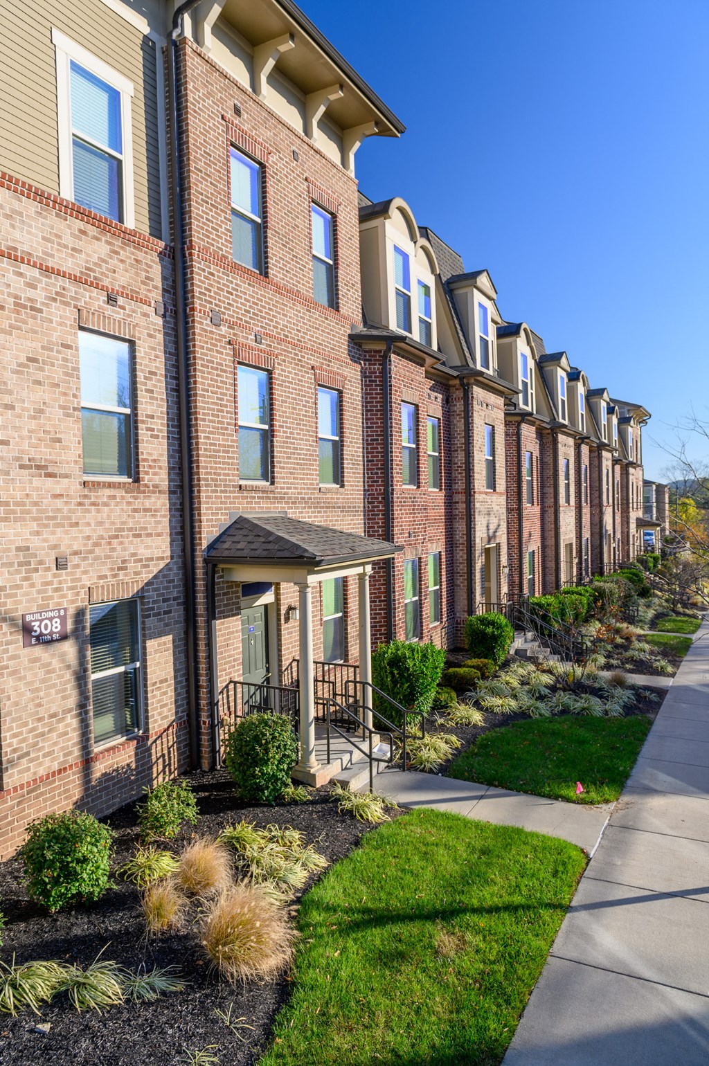 a row of brick apartment buildings on the side of a sidewalk