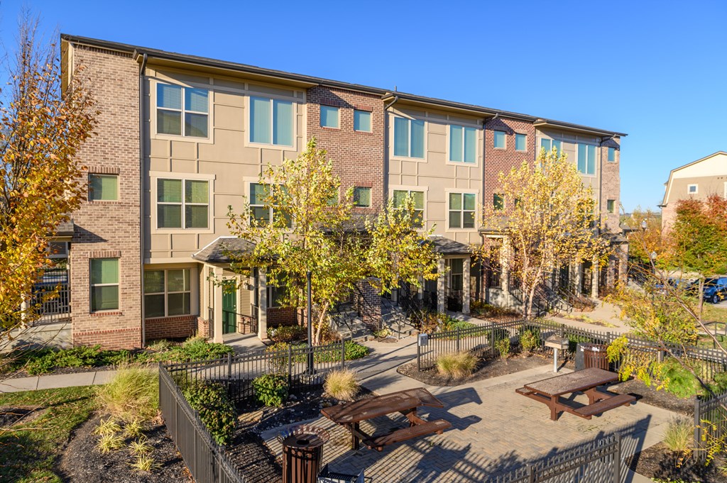 a courtyard with benches and tables in front of an apartment building