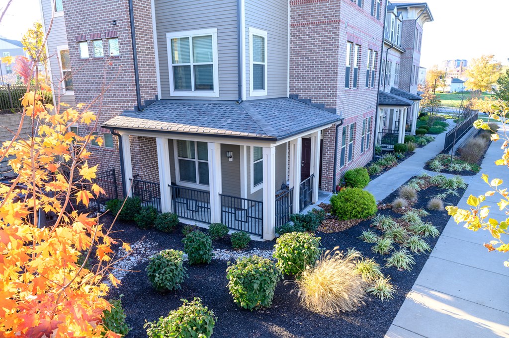 the front yard of an apartment building with a sidewalk and landscaping