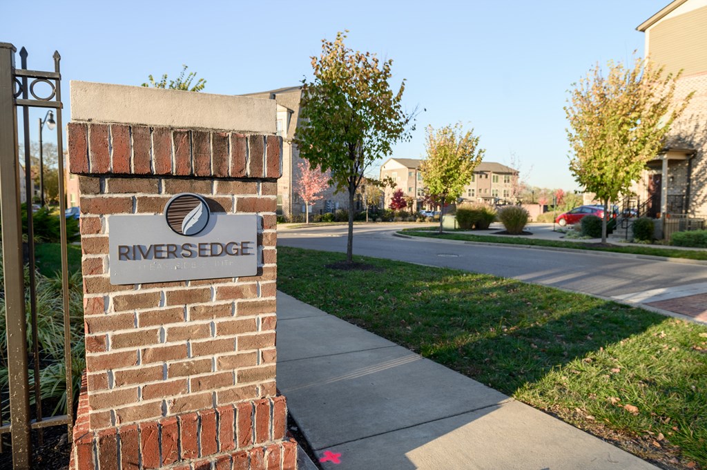 a brick pillar with a street sign on the side of a sidewalk