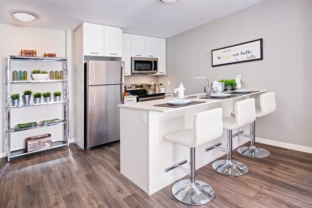 a kitchen with a bar and a stainless steel refrigerator