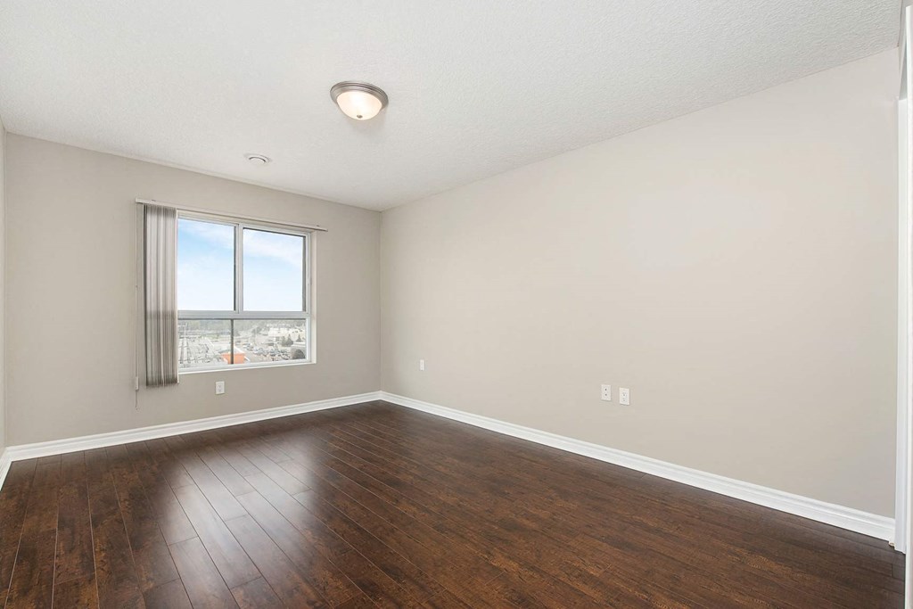 an empty living room with wood floors and a window