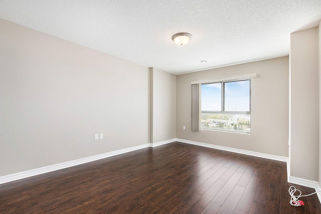 an empty living room with wood floors and a window