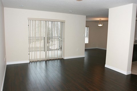an empty living room with wood floors and a sliding glass door