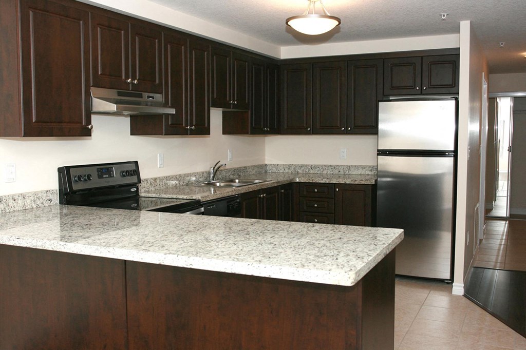 a kitchen with granite counter tops and a stainless steel refrigerator