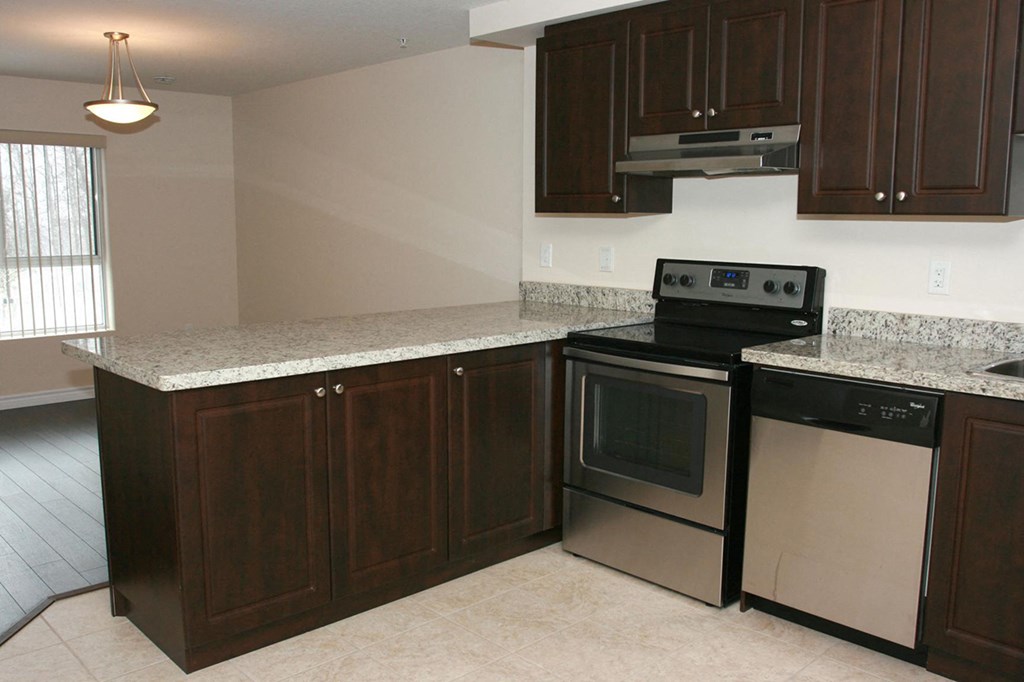 an empty kitchen with stainless steel appliances and granite counter tops