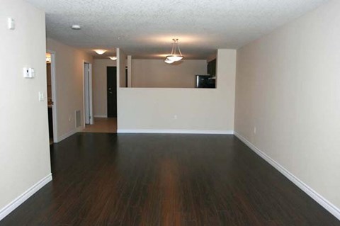 an empty living room with wood floors and white walls