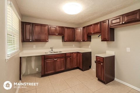 a kitchen with dark wood cabinets and a sink and a window