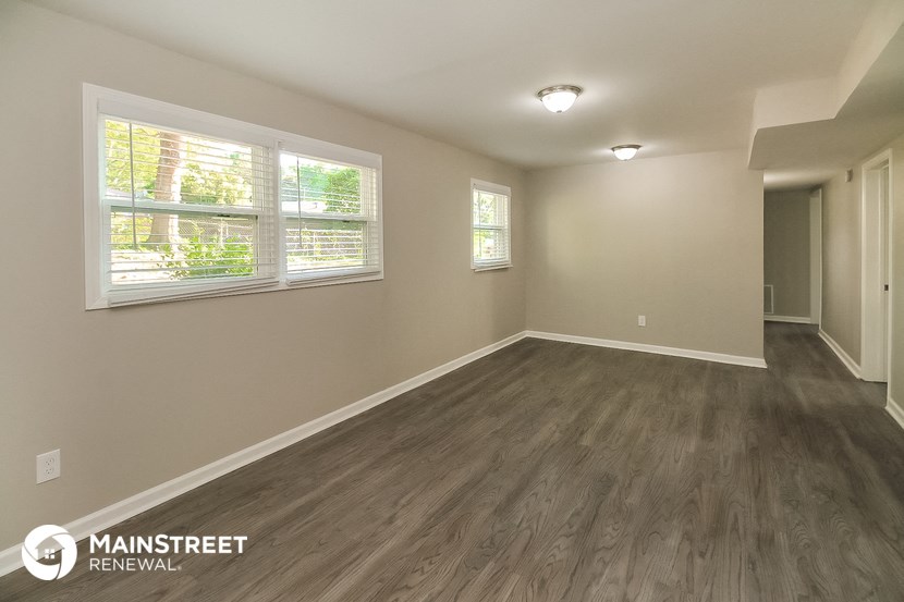 the spacious living room with hardwood flooring and a large window