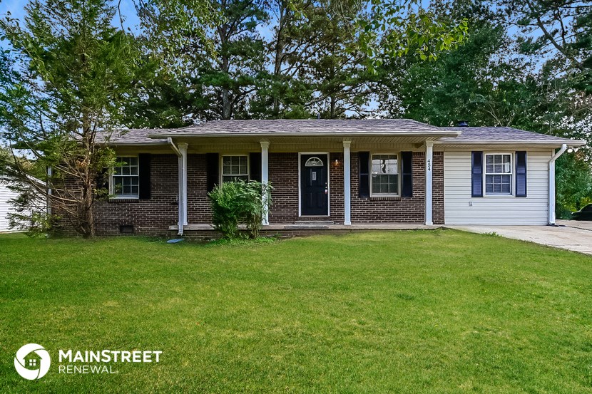 a small brick house with a lawn and a blue door