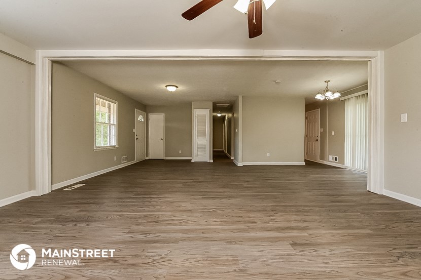 an empty living room with wood floors and a ceiling fan
