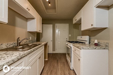 a kitchen with white cabinets and granite counter tops and a sink