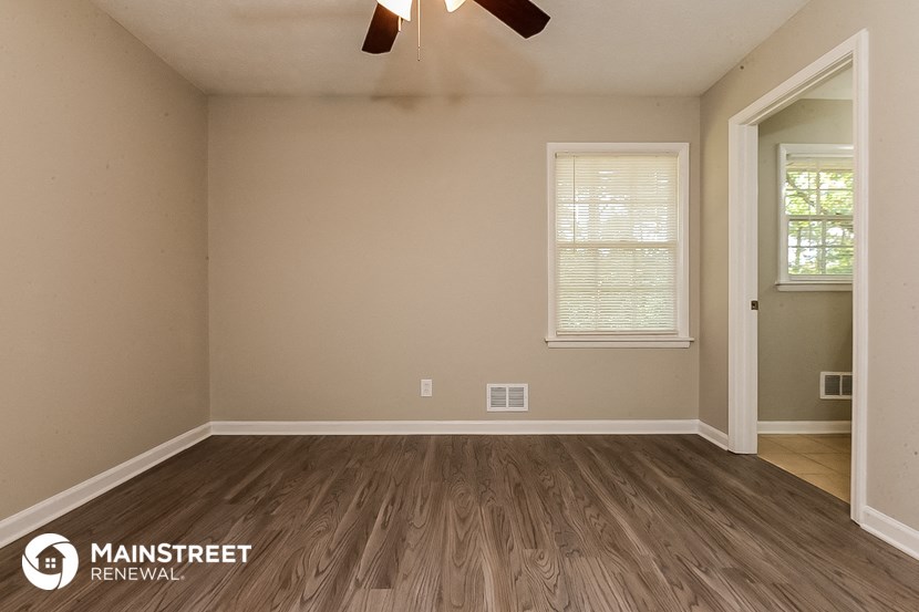 the interior of an empty room with wooden floors and a ceiling fan